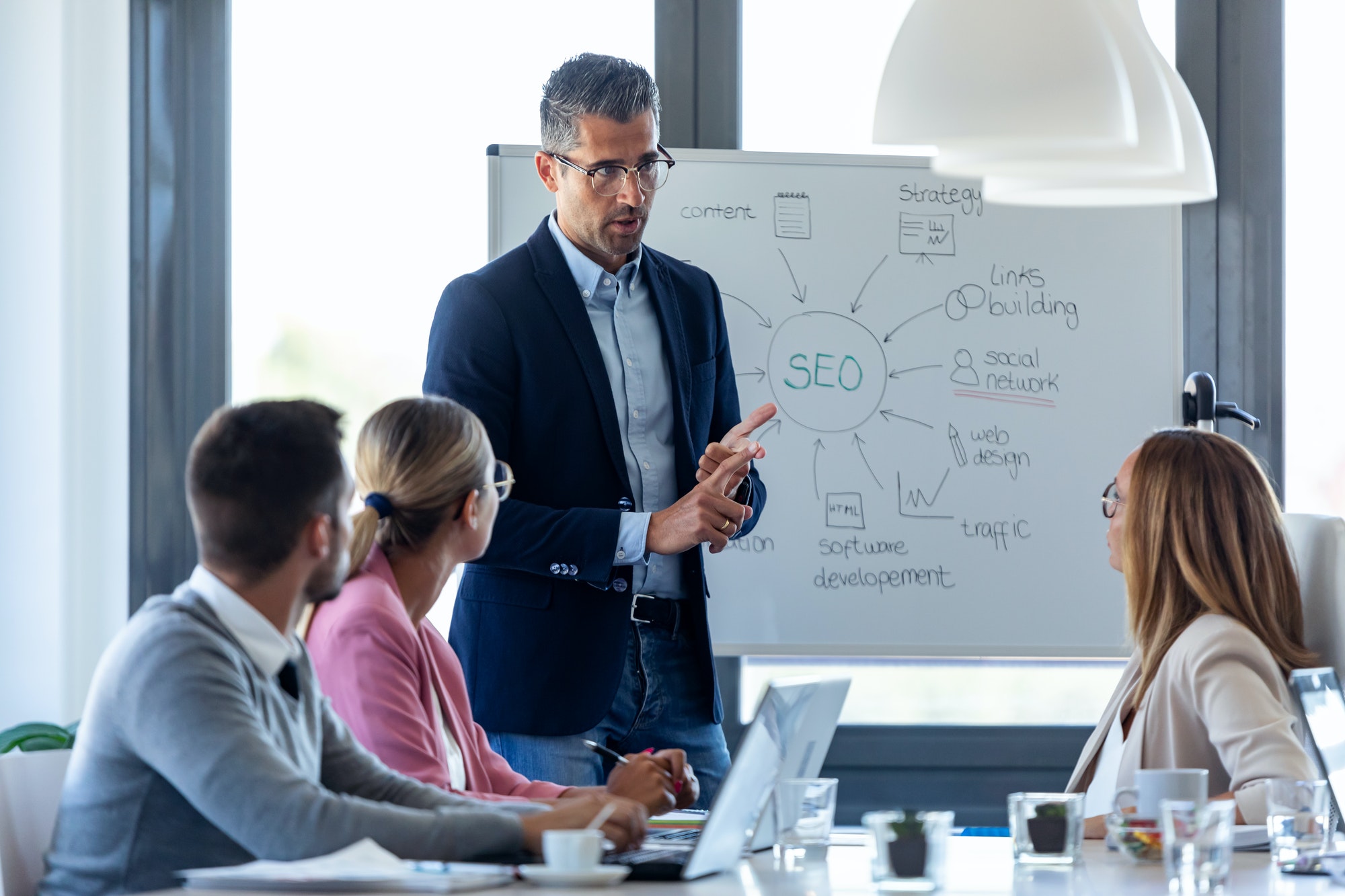 handsome-businessman-explaining-a-project-to-his-colleagues-on-coworking-place-.jpg